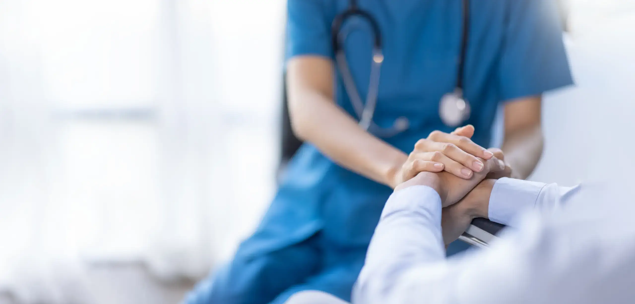 Nurse holds the hand of a patient in palliative care.
