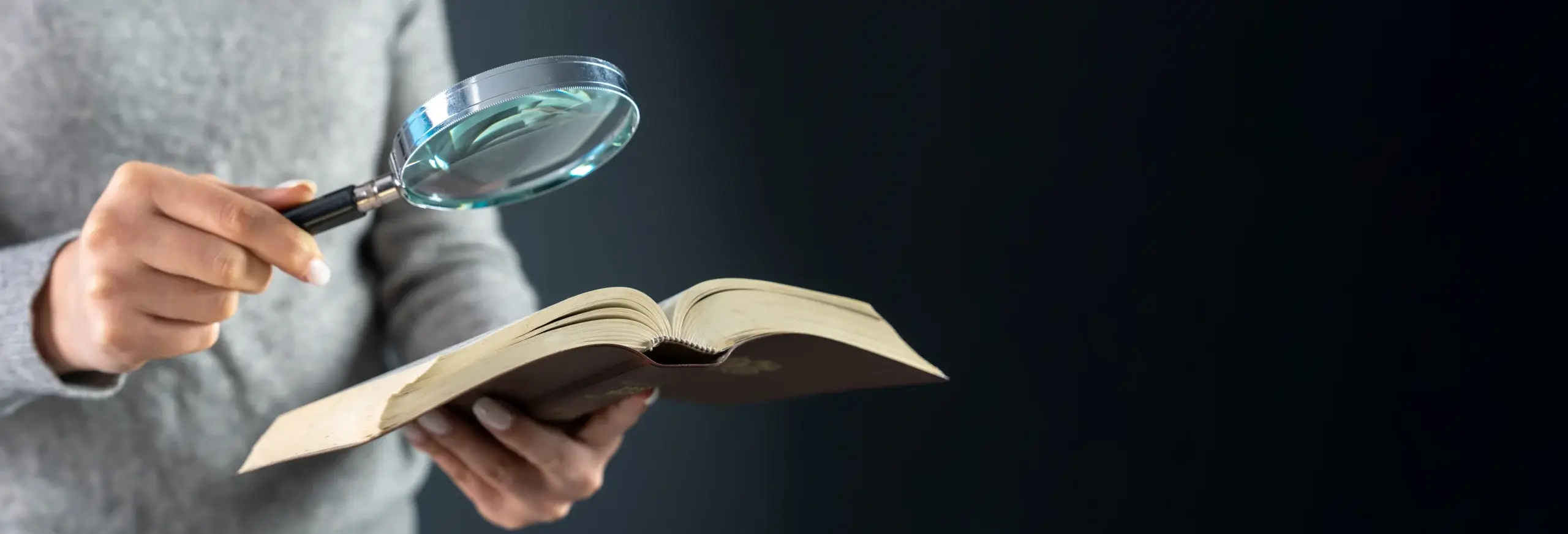 woman looking at a book through a magnifying glass
