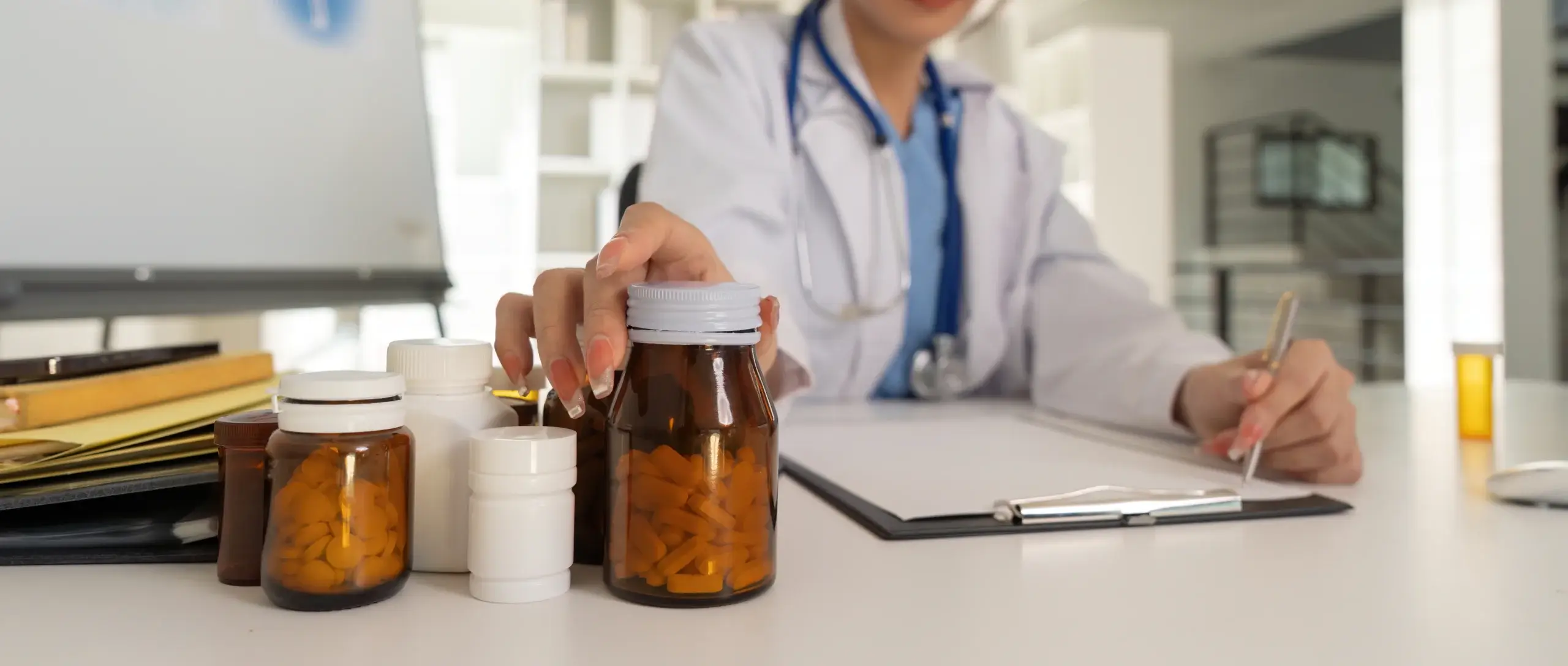 female doctor works at a desk with medicine bottles around her