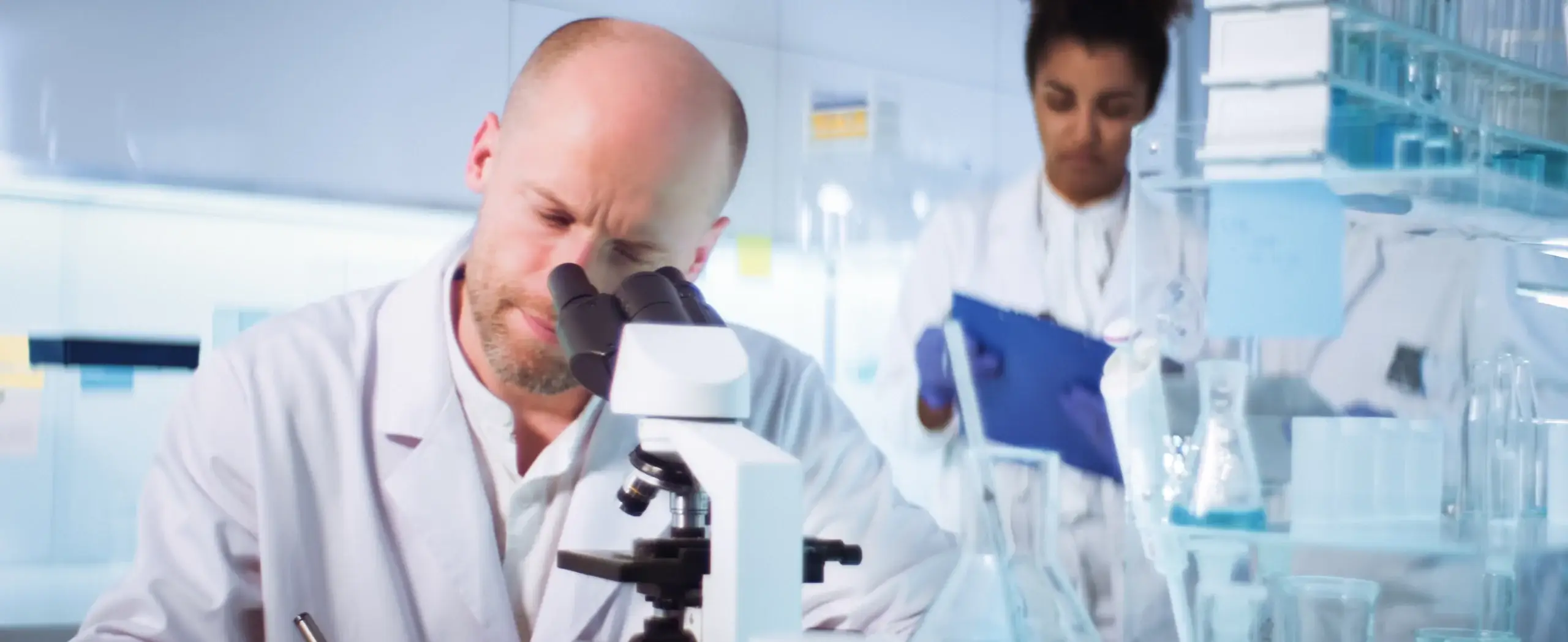 Scientists looking behind microscopes.